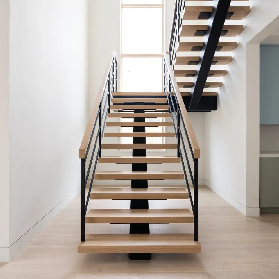 A rebuilt open-riser stair in white oak with a blackened steel rail